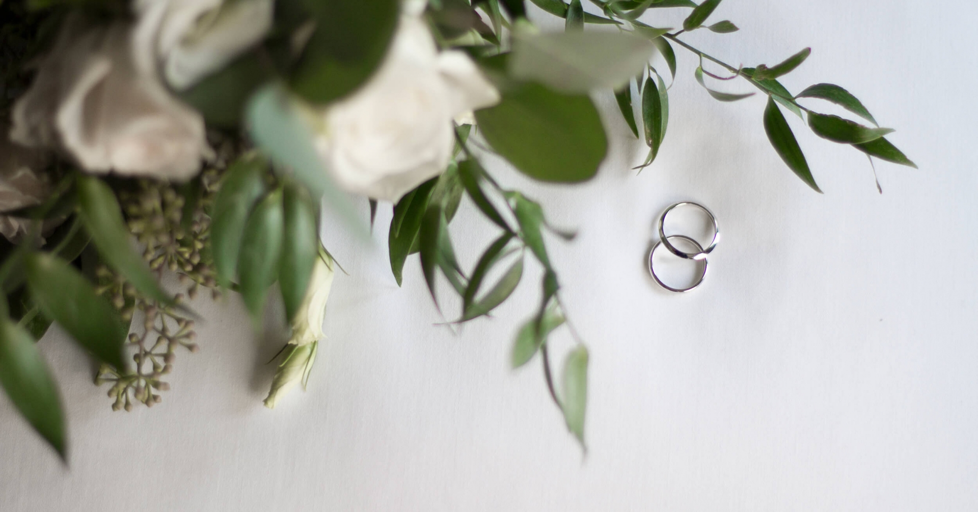 A pair of rings next to a bouquet of flowers