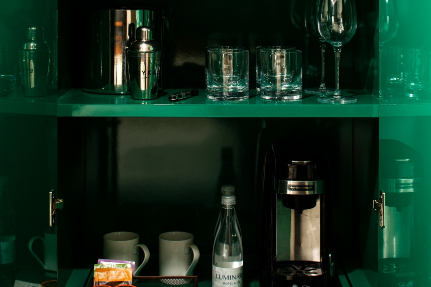 Multiple Bottles on Three Green shelves of Wet Bar in Hotel