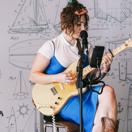 A person playing guitar in front of a microphone