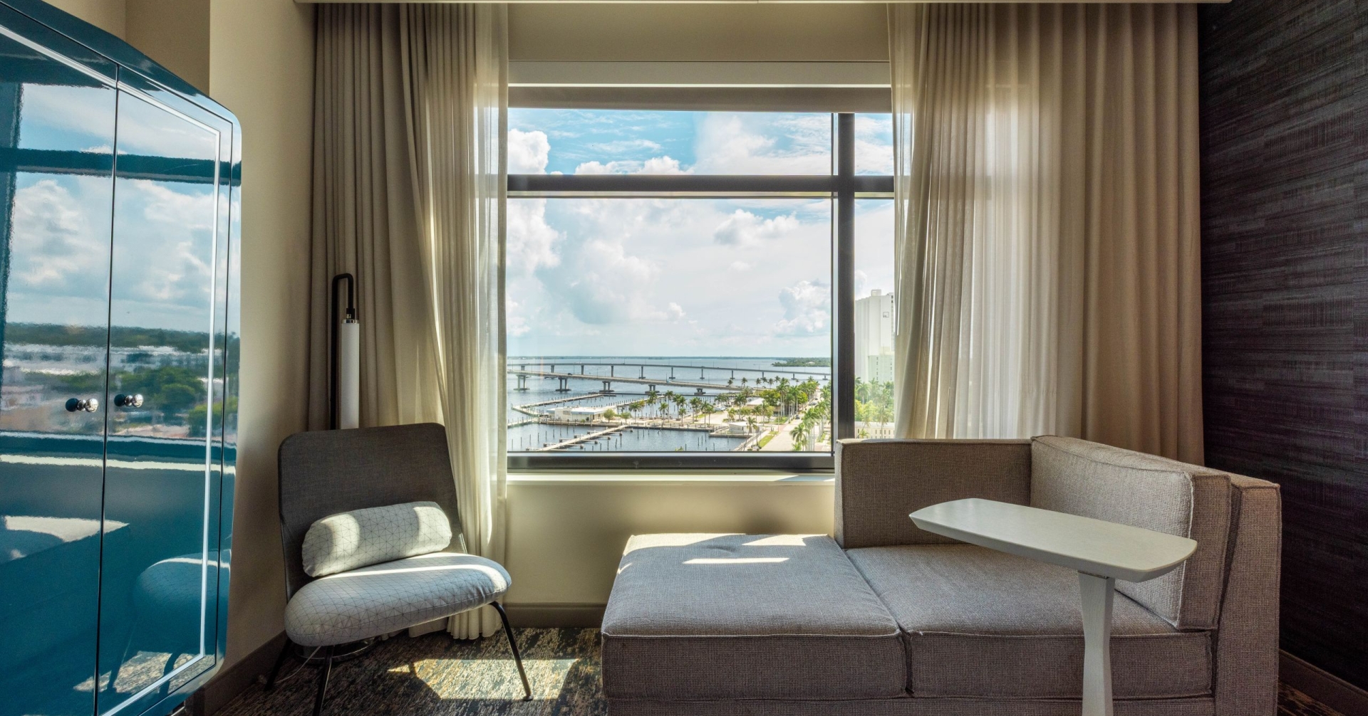 a hotel room chaise lounger with window view or river and marina